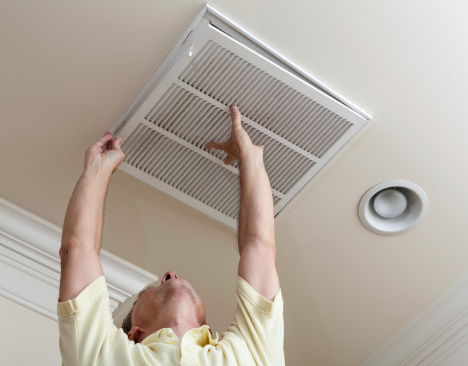 Senior man opening air conditioning filter in ceiling