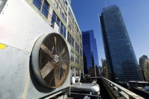 Wide angle view at an outdoor HVAC air conditioner unit located on a high-floor porch of a midtown Manhattan skyscraper.
