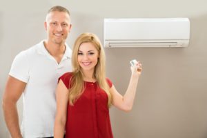 Portrait Of Happy Couple Holding Remote Control Air Conditioner