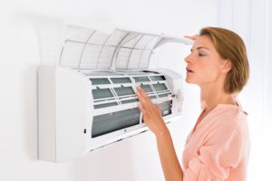 Young Beautiful Woman Opening Air Conditioner At Home