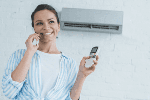 Smiling woman holding AC remote while talking to phone.