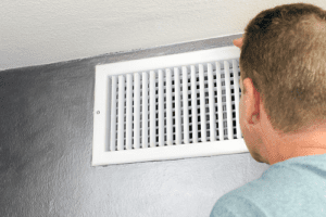 Technician man looking at air vent 