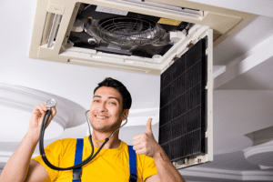 Happy and smiling Ac Technician standing below AC Vent while wearing a stethoscope