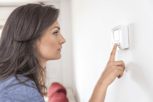 woman hand is touching thermostat 