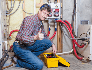 technician kneeling in front of heating system giving thumbs up