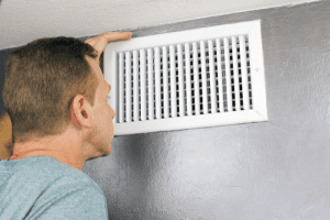 home owner in wondering gesture with hands on HVAC vent 