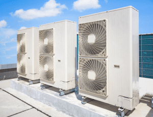 3 White Hvac Units on a roof top with white clouds and blue skies in background