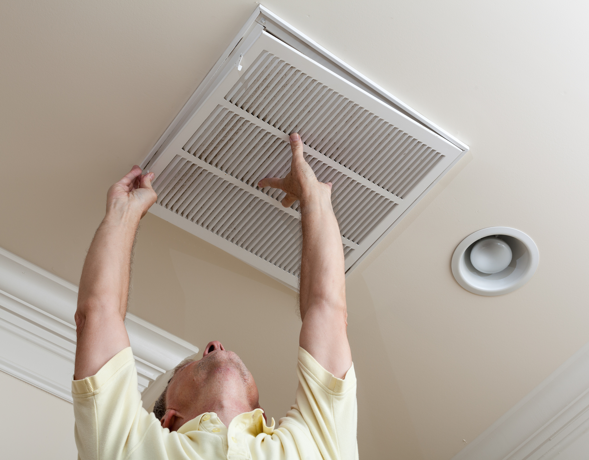 Home Owner looking at white HVAC vent