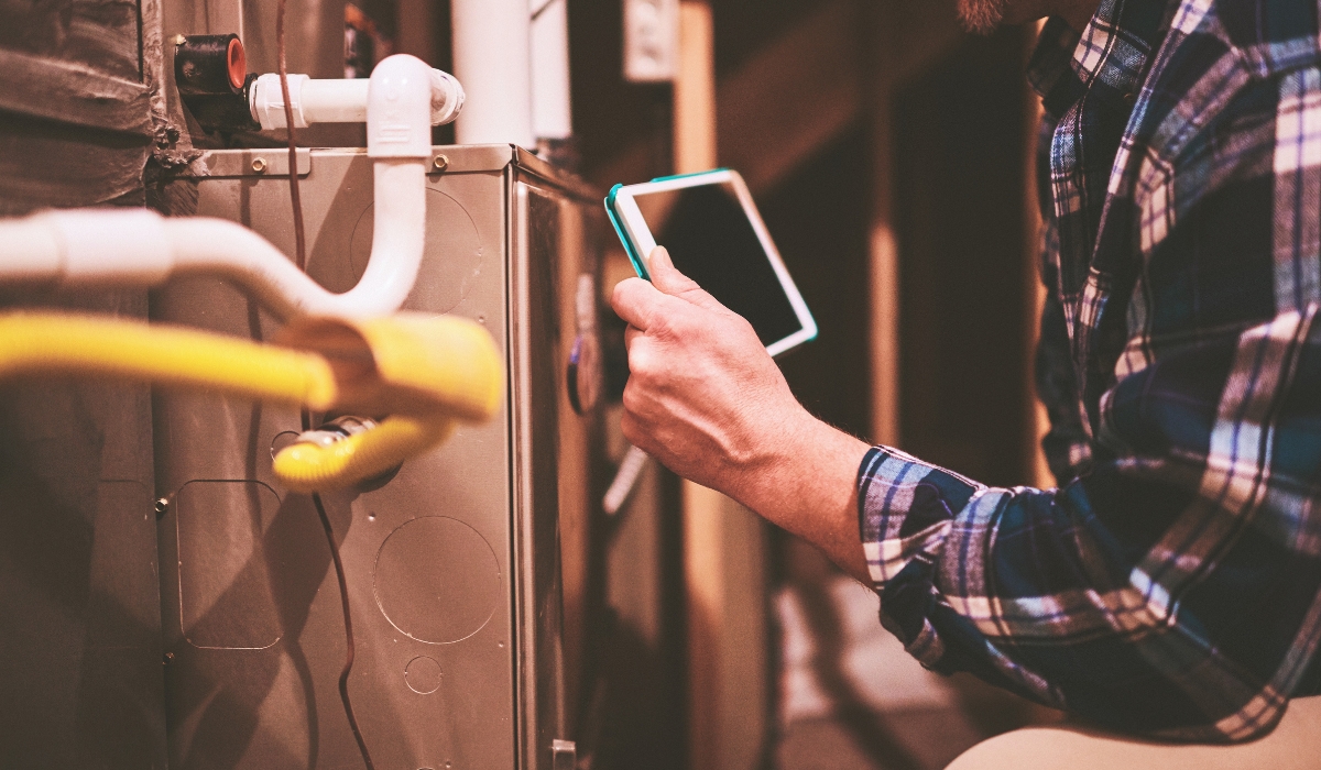 Man using a tablet to help diagnosis furnace