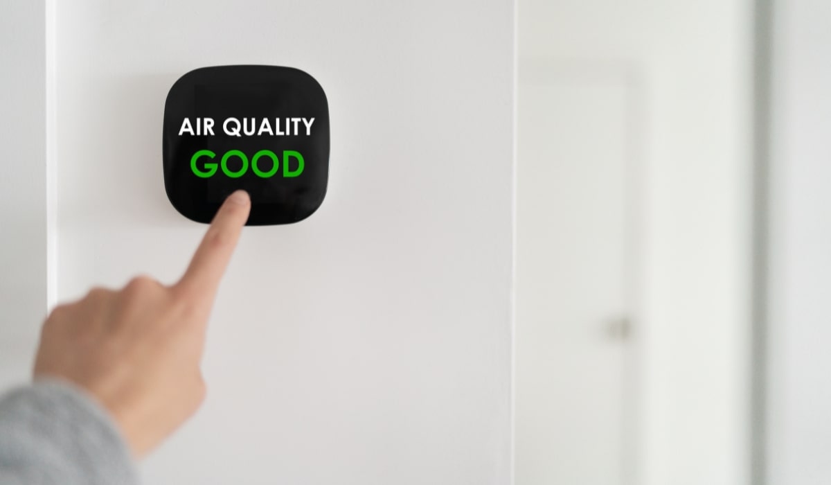Finger pointing to a digital display showing good air quality